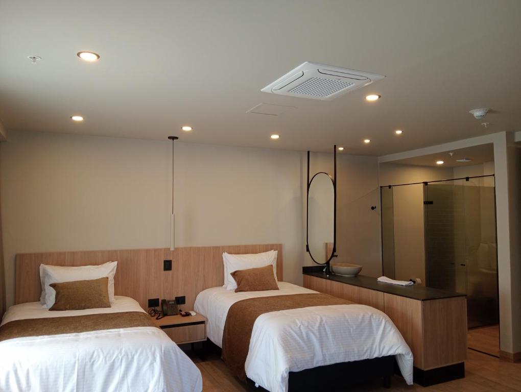 a bedroom with two beds and a mirror at Hotel Rulay Medellin in Medellín