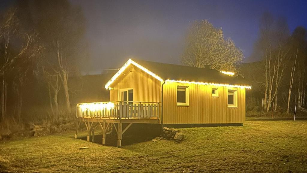 ein kleines Haus mit Licht auf einem Feld in der Unterkunft Det gule huset - Nordic Horn in Brostadbotn