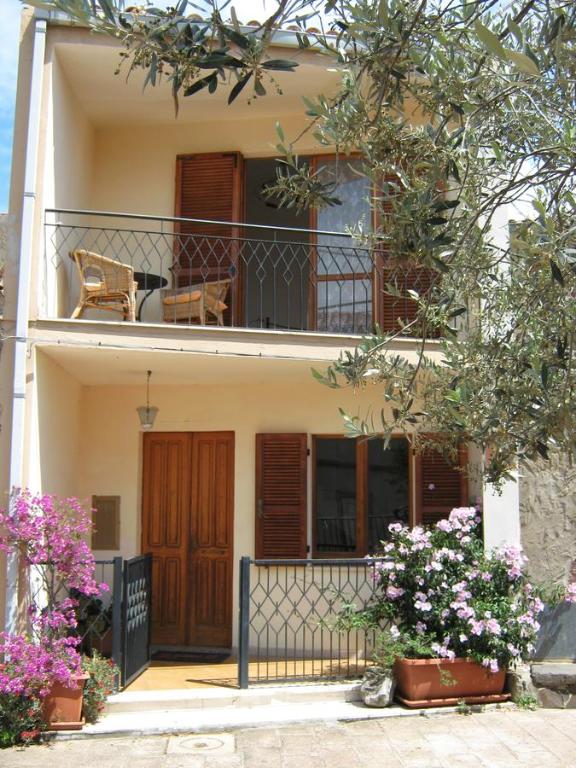 una casa con balcone, sedia e fiori di Casa Bea Bosa/Magomadas a Magomadas