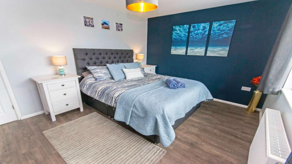 Un dormitorio con una cama y una pared azul. en Sandbanks Braunton, Stylish Cottage near to Saunton Beach Sleeps 4, en Croyde
