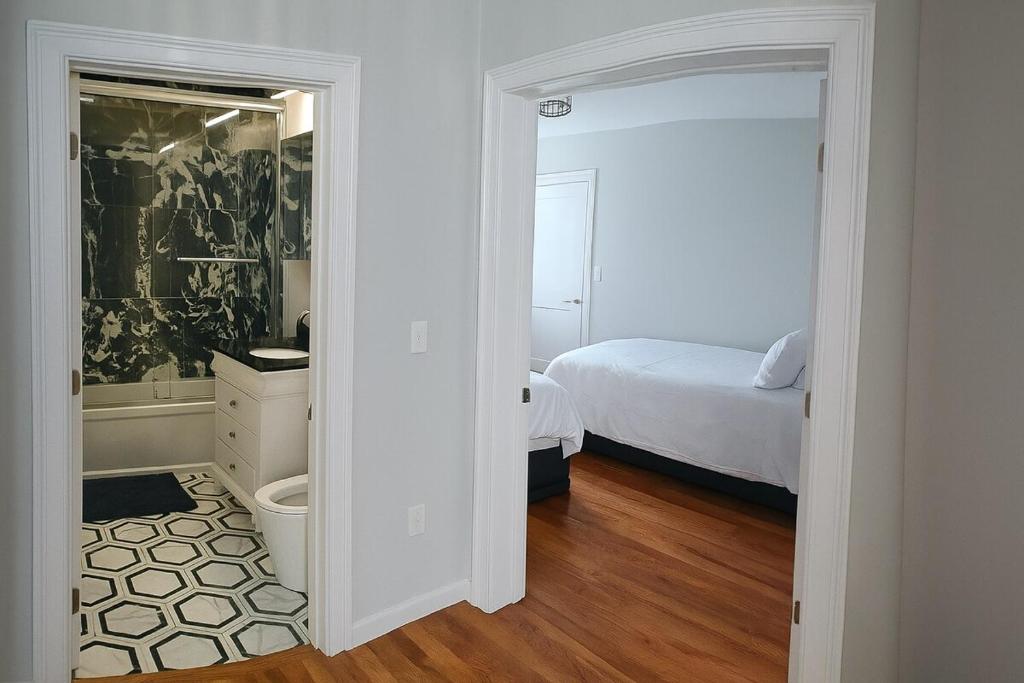 a white bedroom with a bed and a bathroom at Adam's apartment Modern 3BR 2BA Free Parking by Swampscott Beach By Amana Green realty in Swampscott