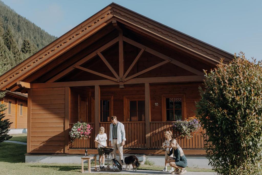 Una familia de pie frente a una pequeña cabaña en Chaletdorf ZellerSee, en Maishofen