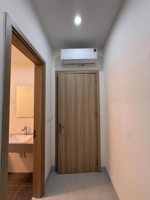 ein Badezimmer mit Holztür und einer Klimaanlage an der Decke in der Unterkunft Creamy home - Homestay Vinhomes Ocean Park 3 in Ðình Loan