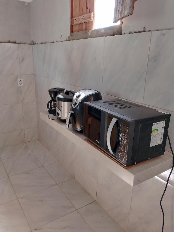 um micro-ondas em uma prateleira de uma cozinha em Pousada degamix em Barroquinha