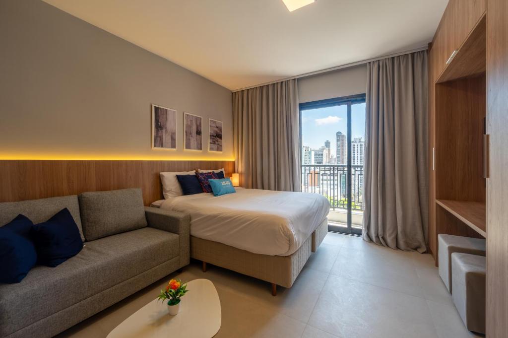 a hotel room with a bed and a couch at Upper West Perdizes by Xtay - Nubank Parque a 500m - antigo Allianz Parque - estúdio moderno com cozinha e vista da cidade in São Paulo
