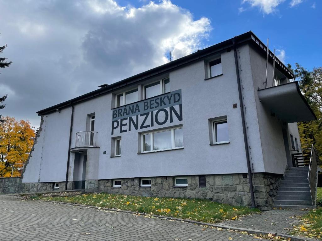 a building with a sign on the side of it at Penzion BránaBeskyd in Frýdlant nad Ostravicí