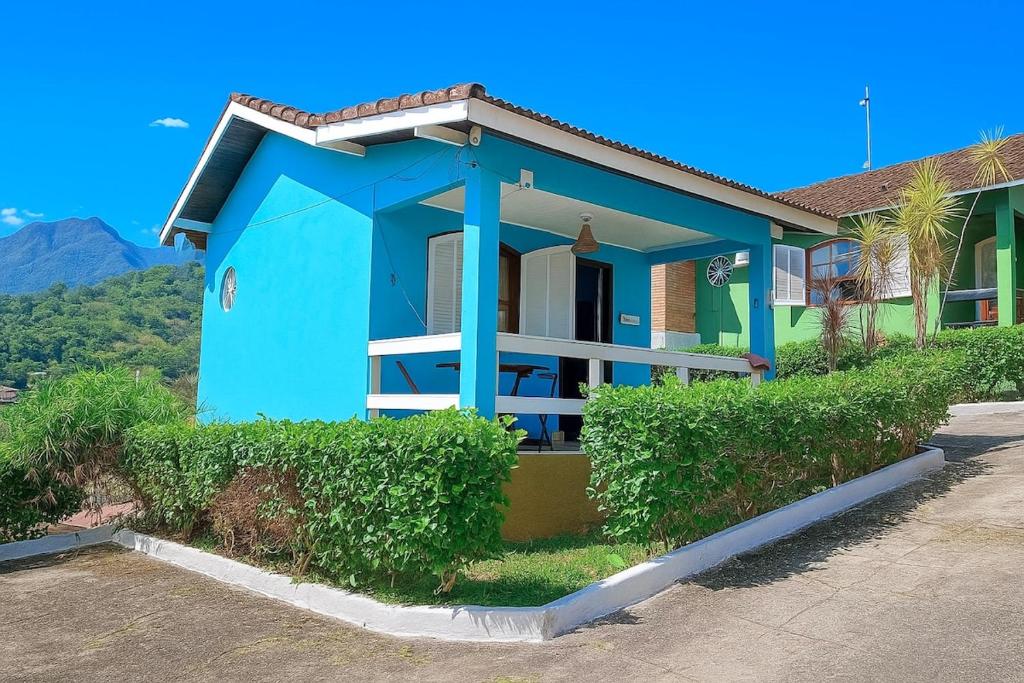 une maison bleue avec des buissons devant elle dans l'établissement Chalé em Penedo - Linda Vista Condomínio, à Itatiaia