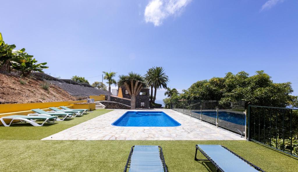 Una piscina con tumbonas y una casa. en Casa Mágica piscina privada, en La Esquinita