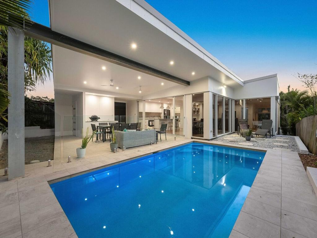 a house with a blue swimming pool in front of it at 3 Moffat Beach Holiday House in Caloundra