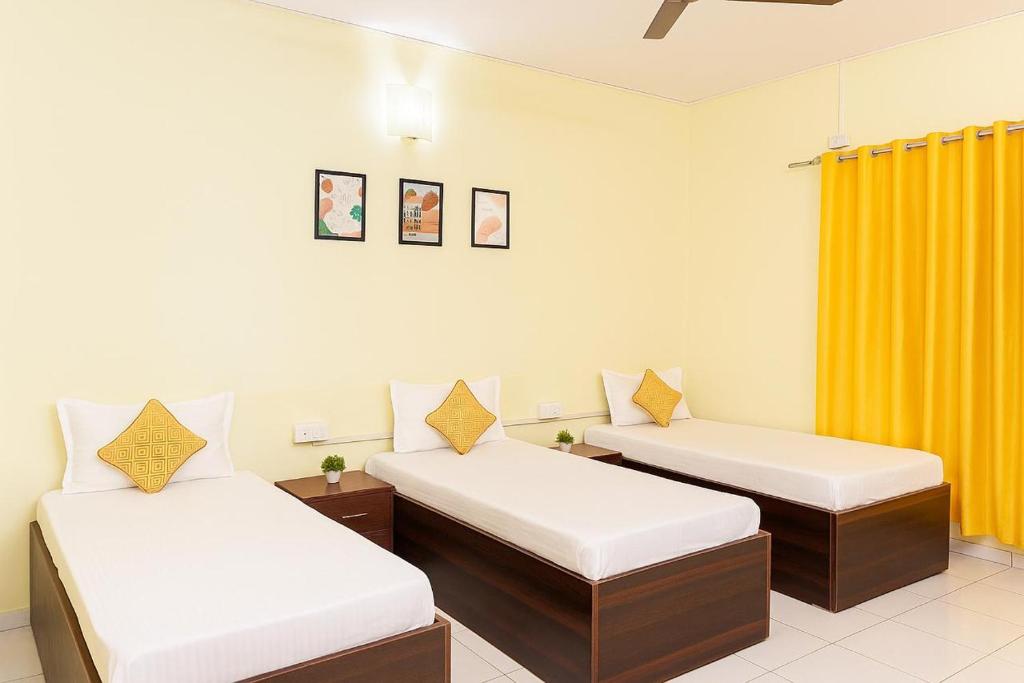 two beds in a room with yellow curtains at Elite Stays Viman Nagar in Pune