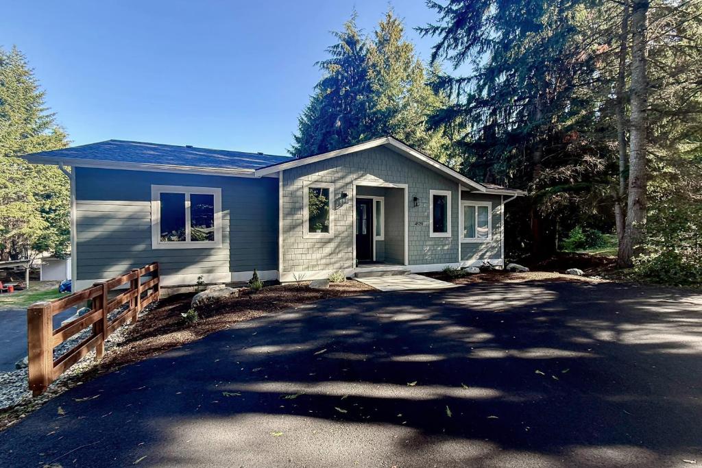 a small blue house with a fence and a driveway at Lake Goodwin Retreat in Lake Goodwin