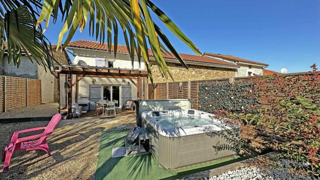 une cour arrière avec un jacuzzi et une chaise rose dans l'établissement Le clos du bon temps, à Sainte-Marie-de-Vaux