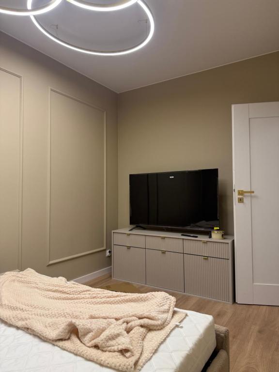 a bedroom with a flat screen tv and a bed at Apartament 69 in Łomża