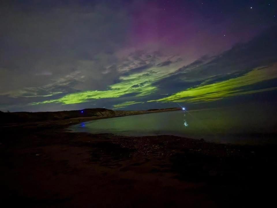 a green light in the sky over a body of water at Luna Retreat - Newbiggin by the Sea in Newbiggin-by-the-Sea