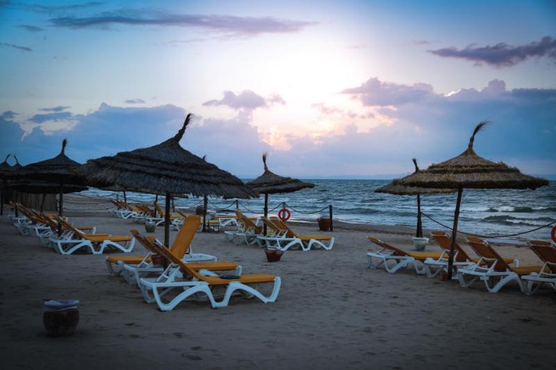 a group of chairs and umbrellas on a beach at Penthouse royale avec piscine privé in Gammarth
