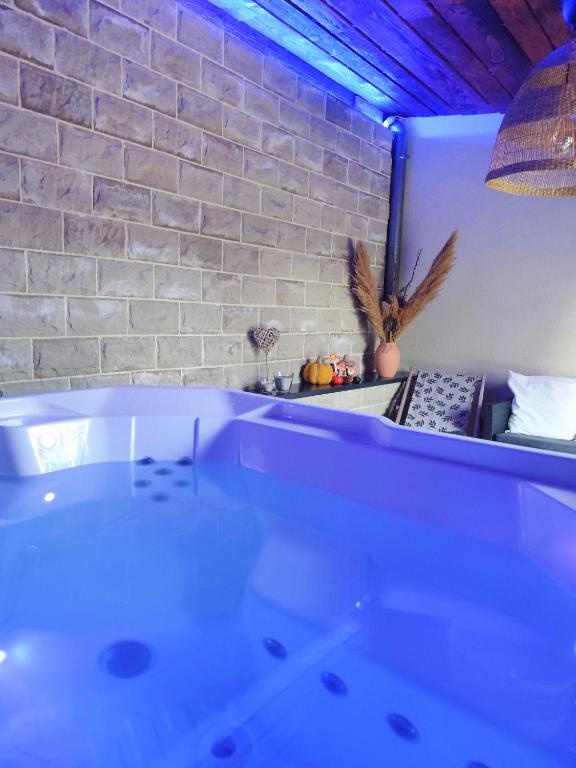 a white bath tub in a room with a brick wall at Doce & Spa proche Colmar in Urschenheim