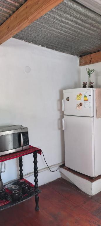 La cuisine est équipée d'un réfrigérateur blanc et d'un four micro-ondes. dans l'établissement Hostal la caleta, à Salta