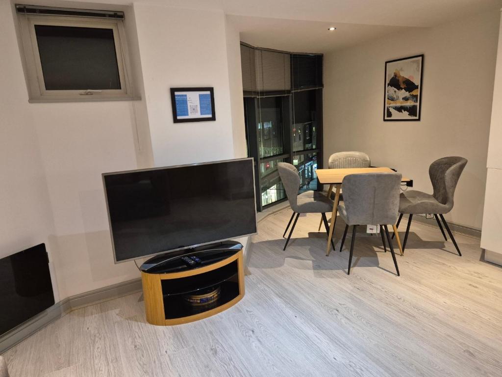 ein Wohnzimmer mit Flachbildfernseher und Tisch in der Unterkunft Entire Flat in York City Centre in York