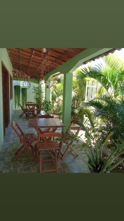 eine Terrasse mit Holztischen, Stühlen und Palmen in der Unterkunft Pousada Recanto da Vila in Mucugê