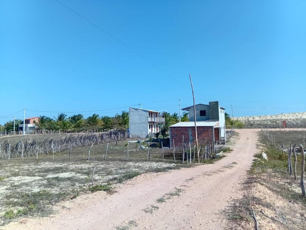 a dirt road in a field with a house at Pousada degamix in Barroquinha