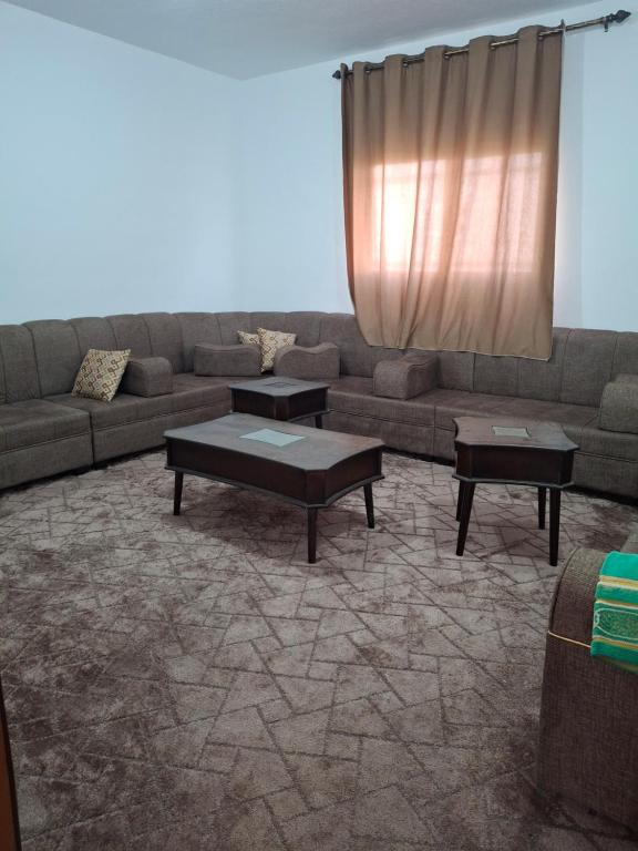 uma sala de estar com um sofá e duas mesas em The Fog mountain em Kerak