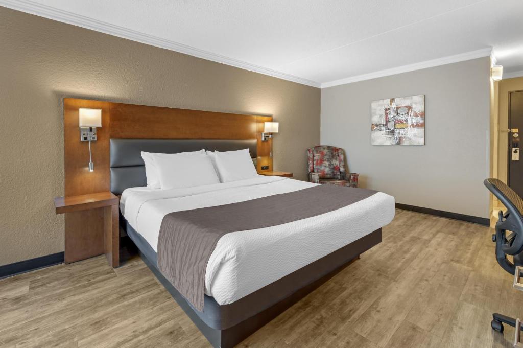 a bedroom with a large bed and a chair at Best Western Hotel Universel Drummondville in Drummondville