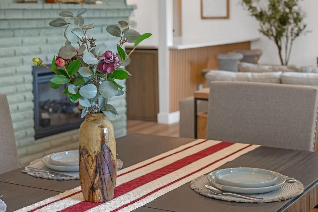 a vase of flowers sitting on a table with plates at Evergreen Garden Wi-Fi available close to Nike Intel Hospital Downtown in Portland