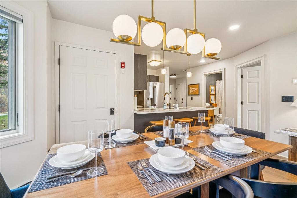 a dining room with a wooden table with plates and glasses at Ski In/Ski Out Pico Resort Unit E106: 3BR newly renovated condo in Telemark Village