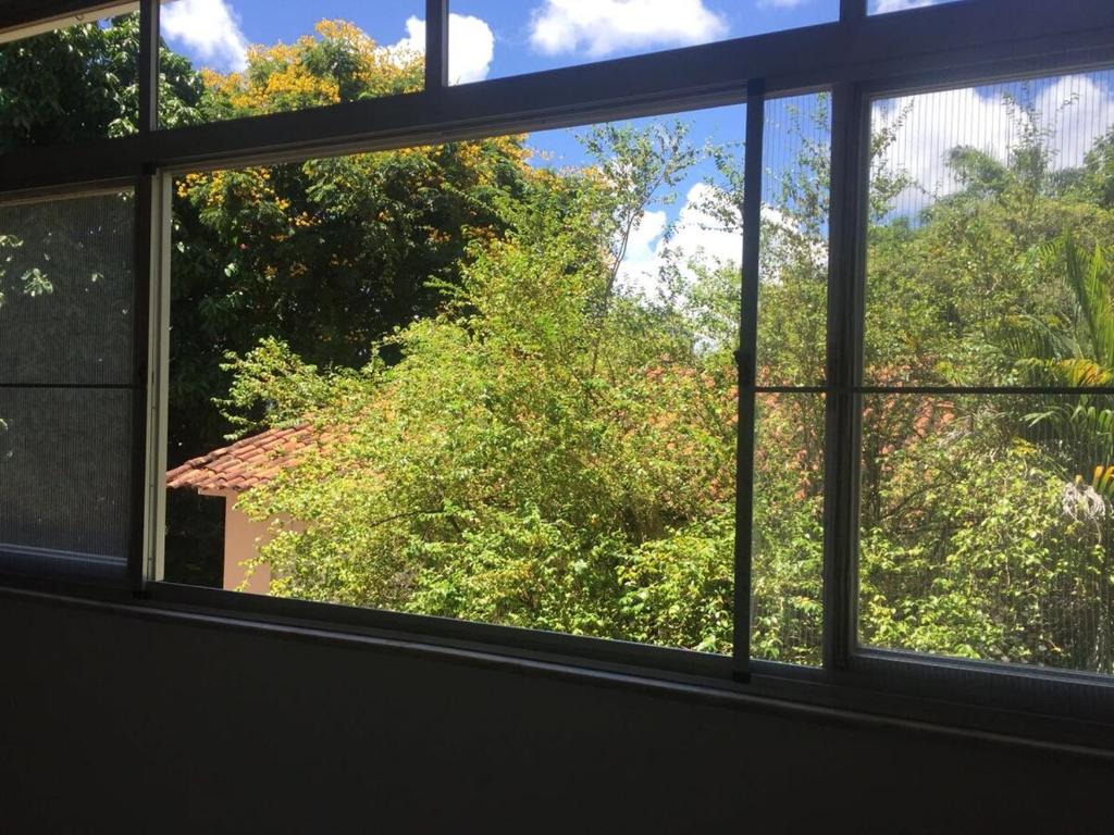 een raam met uitzicht op bomen en een huis bij Circuito dos Trios! in Água Boa