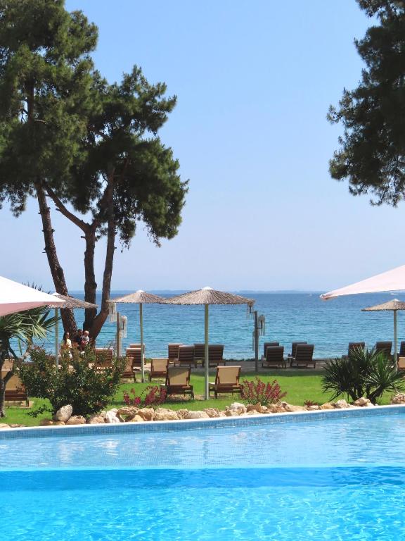 a swimming pool with chairs and umbrellas and the ocean at Aroma Beach Bungalows in Limenas