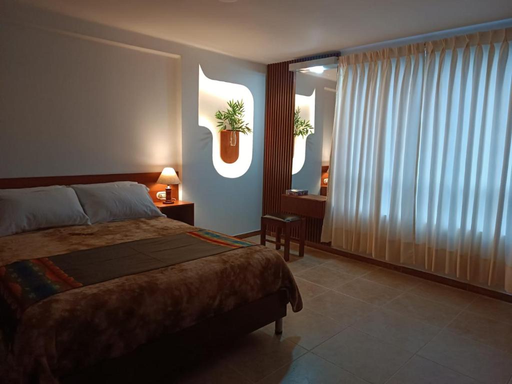 a bedroom with a bed and a window with a plant on the wall at INTI & QUILLA Appartments in Sibundoy