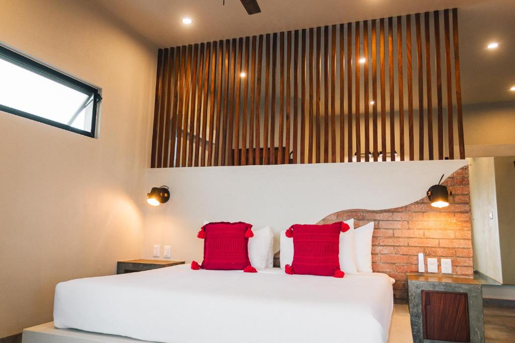 Un dormitorio con una cama blanca con dos almohadas rojas. en The Garden Suite, en El Rebalse