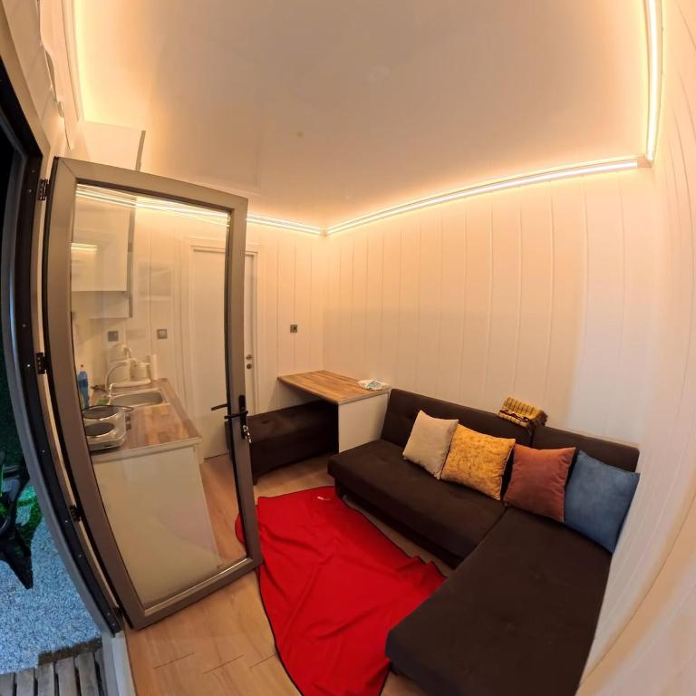 a living room with a black couch and a red blanket at Cap tiny house in Buca