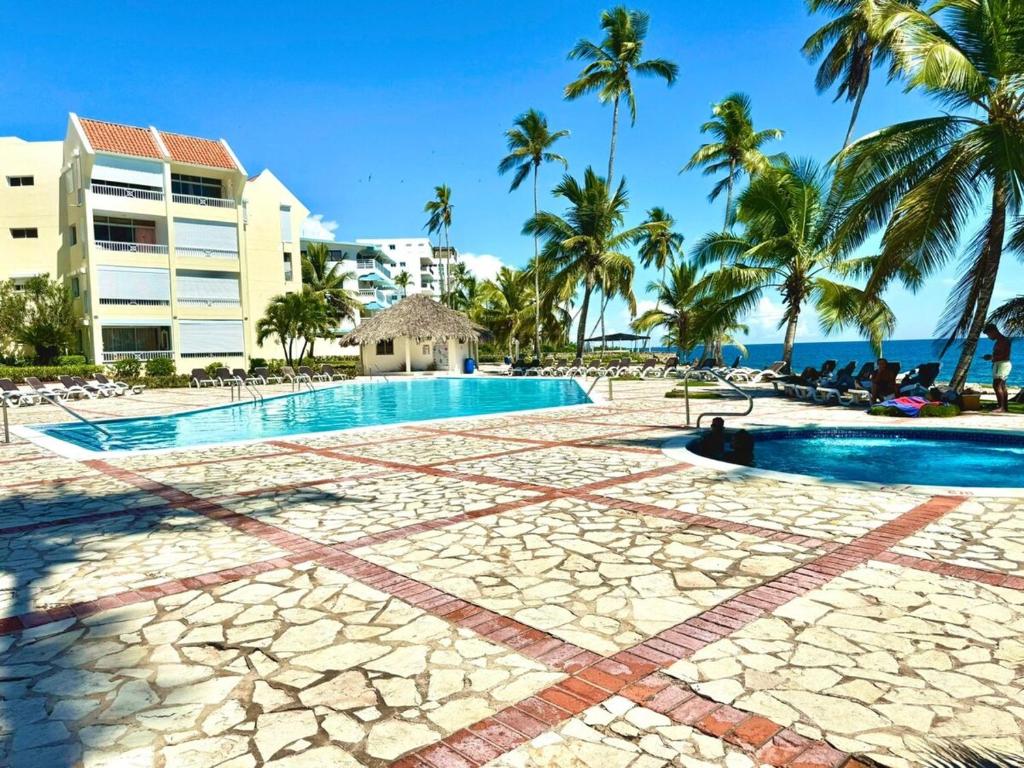 a resort pool with palm trees and the ocean at ocean view juan dolió in La Puntica de Juan Dolio