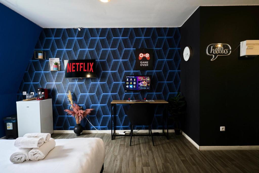 a bedroom with a blue wall with a computer on a desk at NG Prestige - Lille I Roubaix Centre I Grande Rue - Studio - Netflix & Wifi in Roubaix