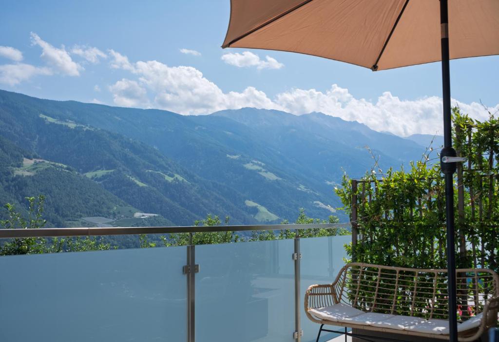 a chair and an umbrella on a balcony with a view at Texlhof - Stella Alpina in Parcines