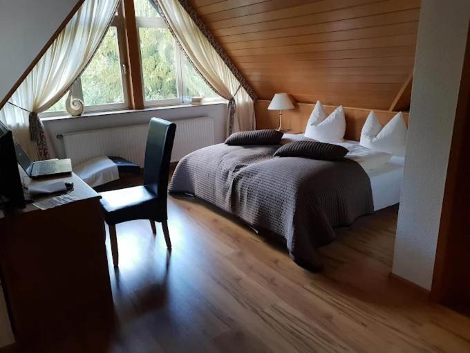 a bedroom with a bed and a desk and a window at Hotel Haus Niggemann in Hattingen