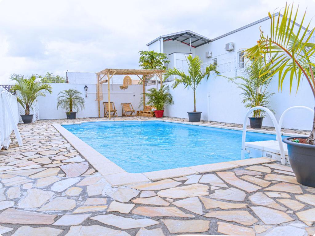 a swimming pool in front of a house with plants at Le Mohana - L'évasion tropicale de l'Est in Saint-André