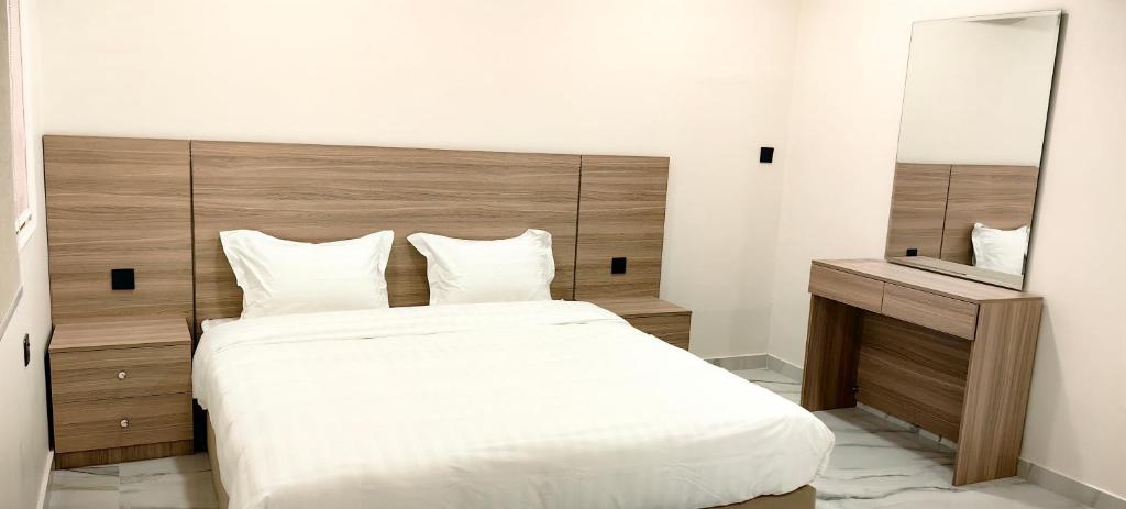 a bedroom with a large white bed and a mirror at قمة قباءلشقق in Al Madinah