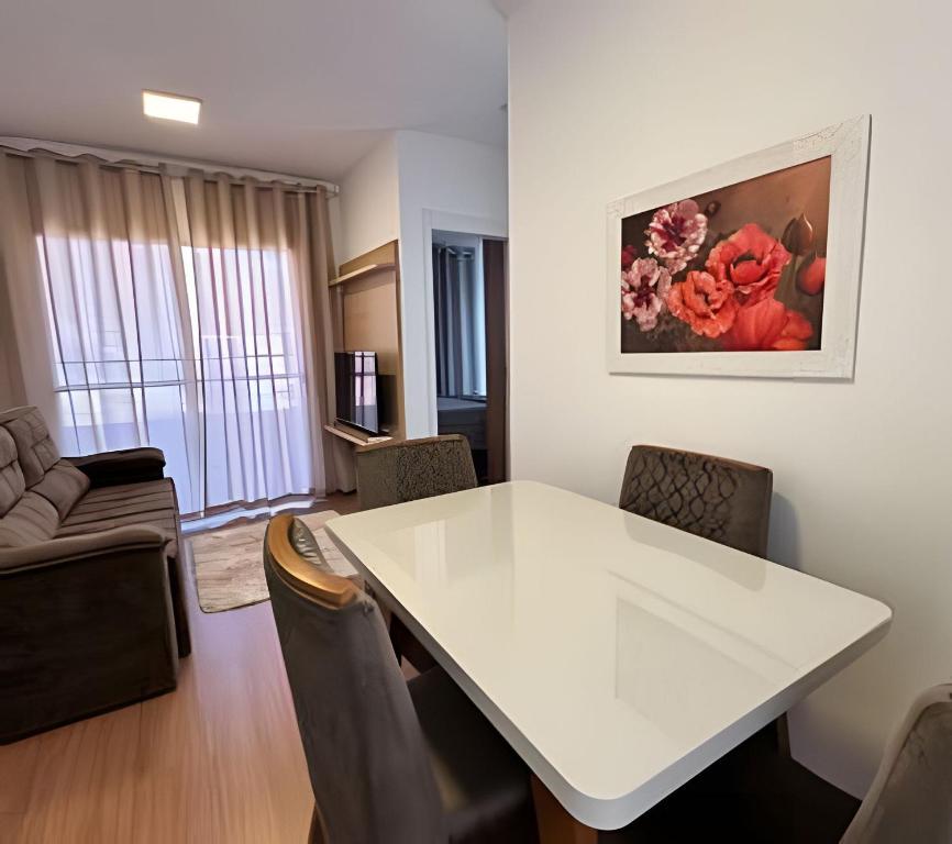 uma sala de estar com uma mesa e cadeiras brancas em Plano 22 Prime Loft em Extrema