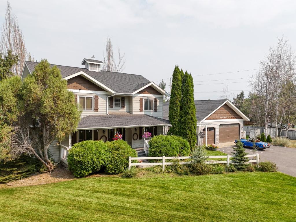 a house with a white fence in a yard at Country Way Inn in Kalispell