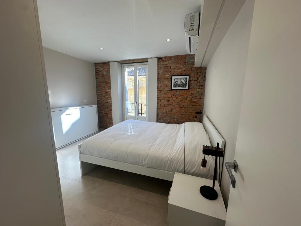 a bedroom with a white bed and a brick wall at Casa PORTA LANERO di Francesco e Alessandro in Nizza Monferrato