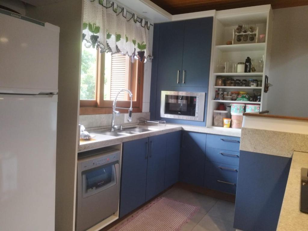 a kitchen with blue cabinets and a sink at Xixo Casa do Vale Descanso e Natureza Em Gramado in Gramado
