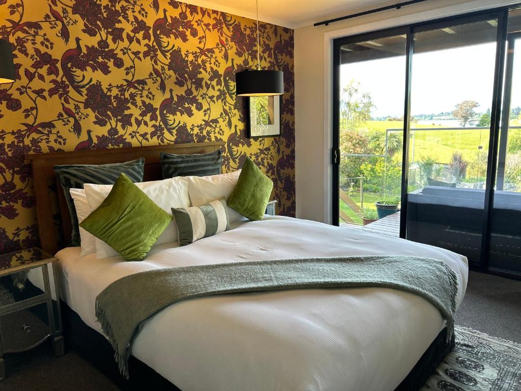 Un dormitorio con una cama grande con almohadas verdes. en Incredible mountain & sea views, en Mapua