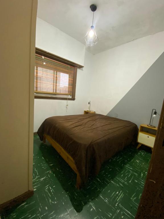 een slaapkamer met een bed en een groene vloer bij Departamento 2 ambientes en MIRAMAR in Miramar