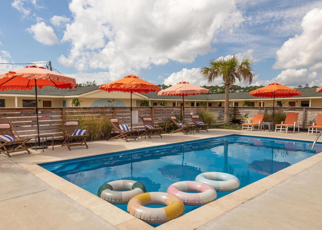 een zwembad bij een hotel met stoelen en parasols bij Driftwood Motel in Bay Saint Louis