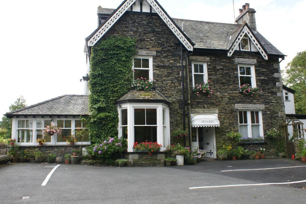 een stenen huis met bloemen op een parkeerplaats bij Glencree in Windermere