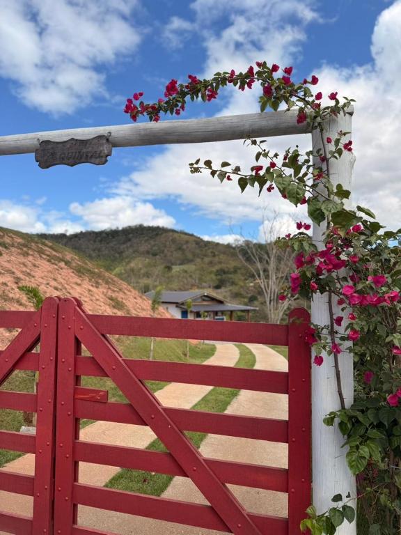 a red fence with pink flowers on it at Casa Quintal Sebollas - Paraíba do Sul in Paraíba do Sul