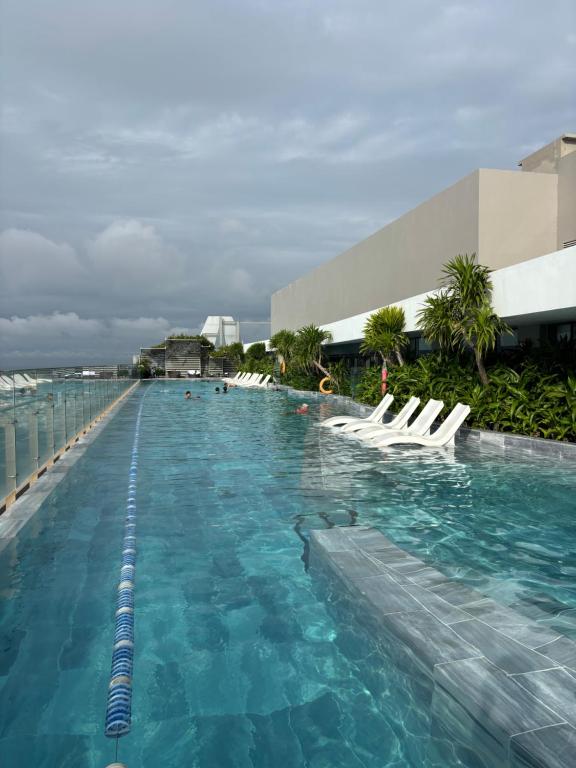 a swimming pool with white chairs in the water at The Sóng Homestay Vibes by the Sea in Vung Tau