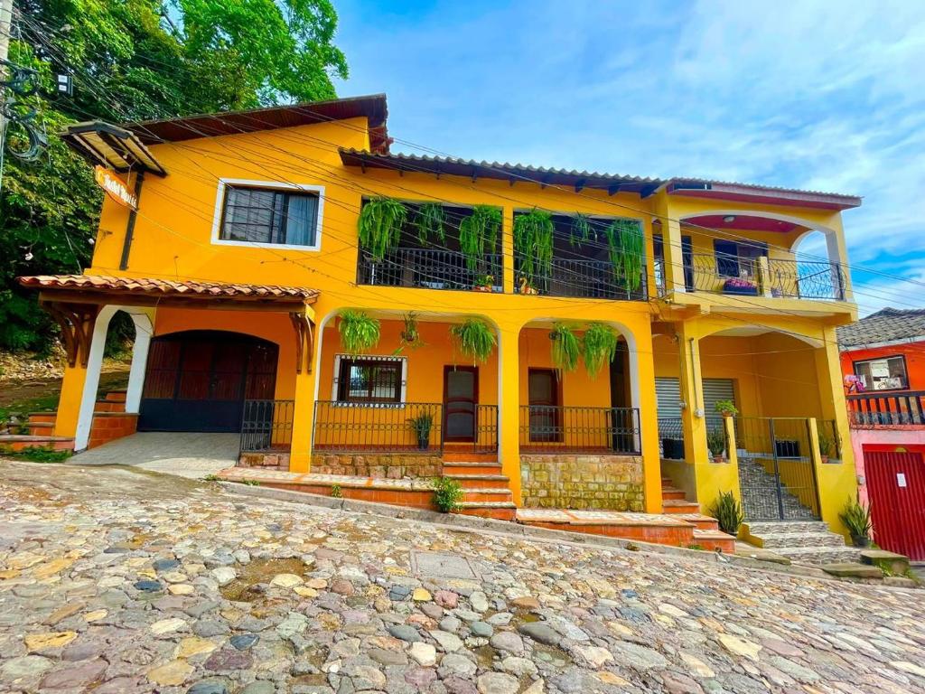 een geel huis met een rood hek ervoor bij Hostal Marias in Copan Ruinas